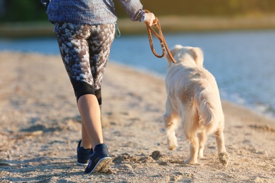 Young woman with her dog together on beach. Pet care