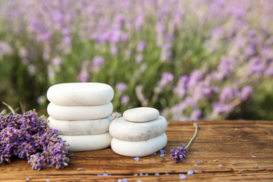 Photo of Spa stones, fresh lavender flowers and bath salt on wooden table outdoors, closeup