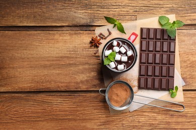 Photo of Mug of delicious hot chocolate with marshmallows and fresh mint near ingredients on wooden table, top view. Space for text