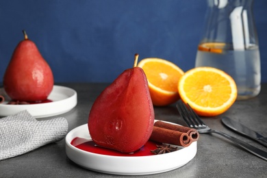 Photo of Plate with red wine poached pear and spices on grey table