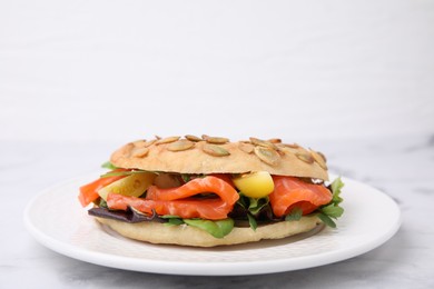 Photo of Tasty bagel with salmon and tomatoes on white marble table, space for text