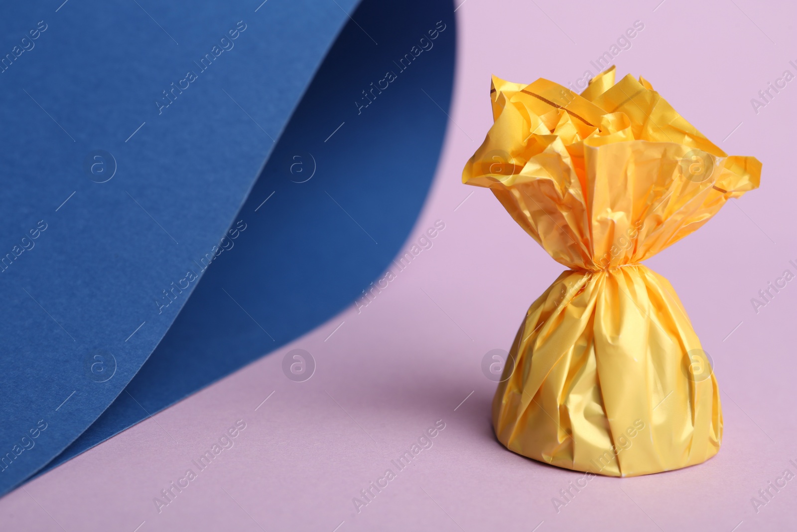 Photo of Candy in yellow wrapper on color background. Space for text