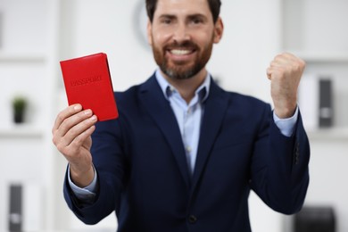 Photo of Immigration. Happy man with passport indoors, selective focus