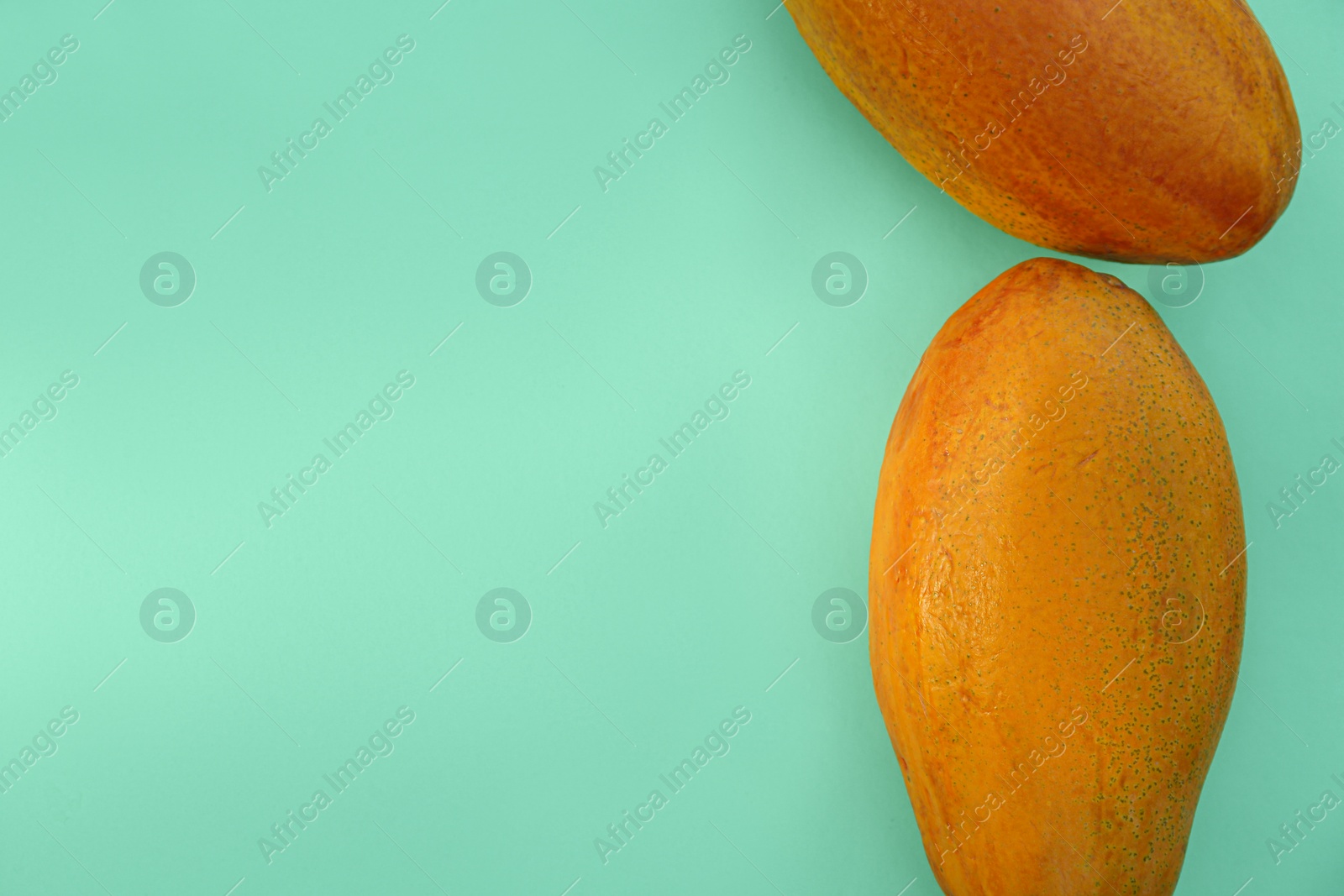 Photo of Fresh ripe papaya fruits on light turquoise background, flat lay. Space for text