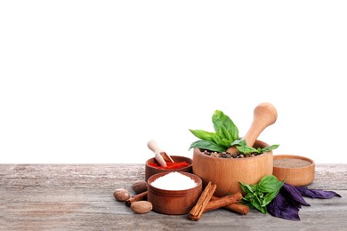Mortar and different spices on wooden table against white background. Space for text