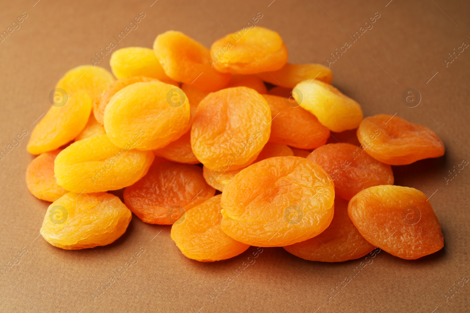 Photo of Many tasty dried apricots on pale brown background, closeup. Healthy snack