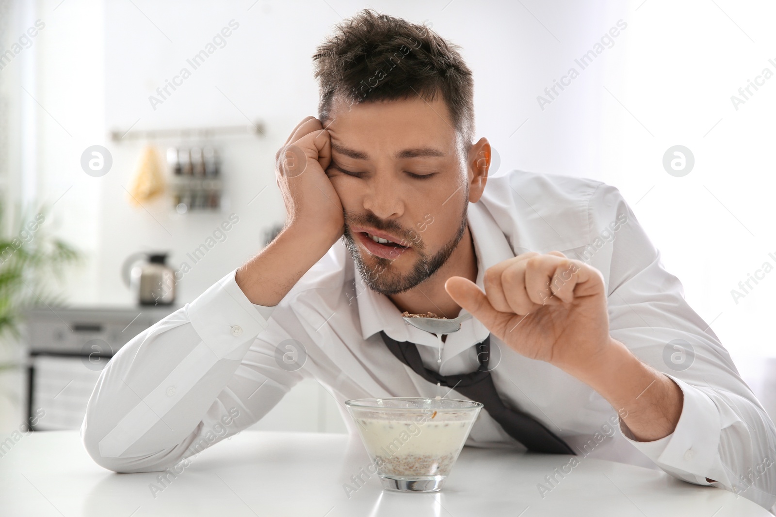 Photo of Sleepy man eating breakfast at home in morning