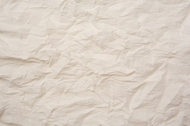 Photo of Texture of crumpled beige paper as background, closeup view