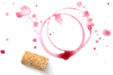 Photo of Red wine rings, drops and cork on white background, top view