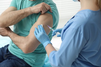 Photo of Doctor giving hepatitis vaccine to patient in clinic, closeup