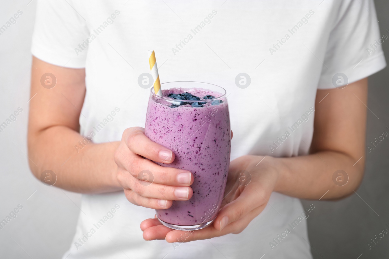 Photo of Woman holding glass of delicious blueberry smoothie, closeup