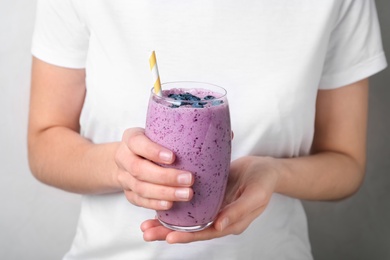 Photo of Woman holding glass of delicious blueberry smoothie, closeup