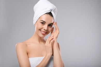 Photo of Happy young woman with towel on head against light grey background, space for text. Washing hair