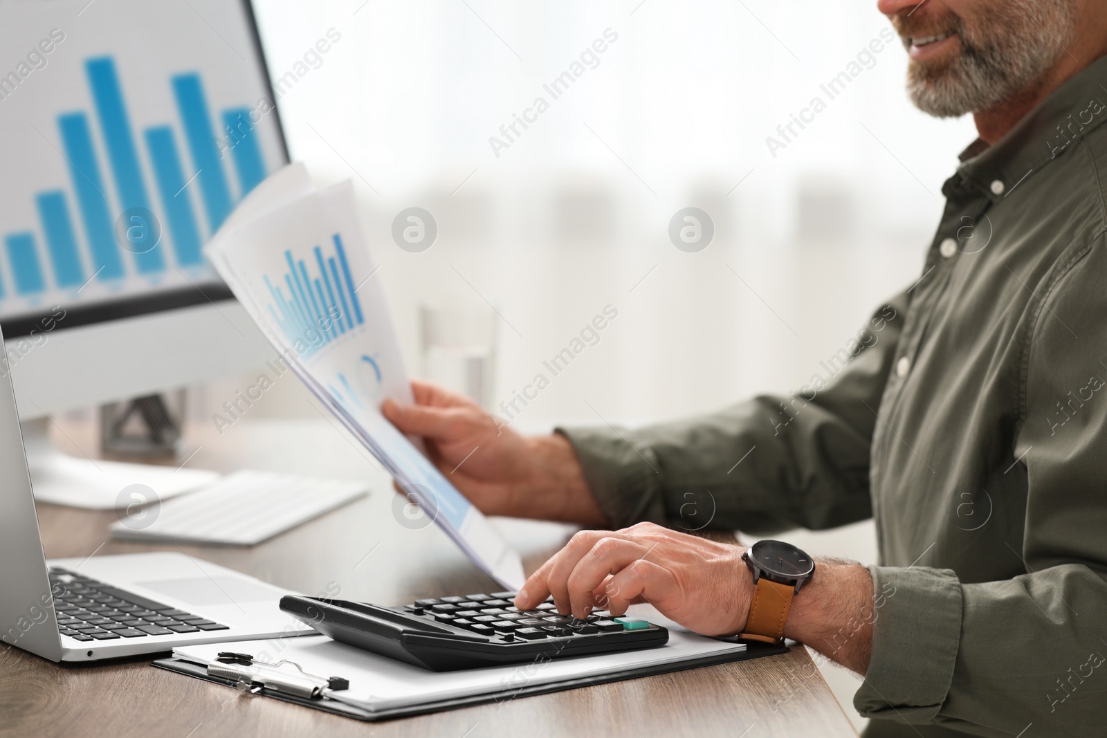 Photo of Professional accountant using calculator at wooden desk in office, closeup