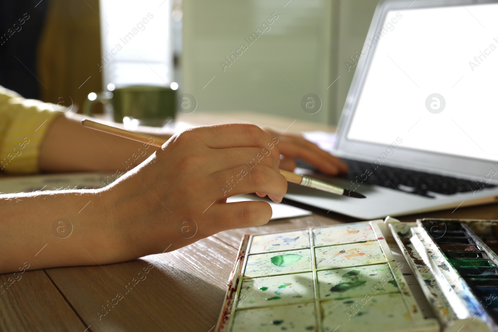 Photo of Woman drawing with paints at online art lesson indoors, closeup. Distant learning