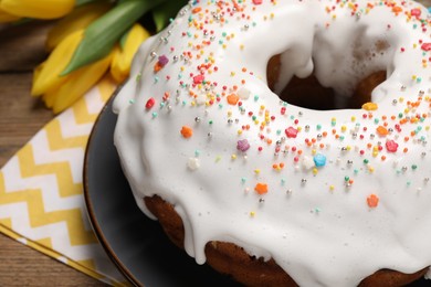 Easter cake with sprinkles and tulips on wooden table, closeup