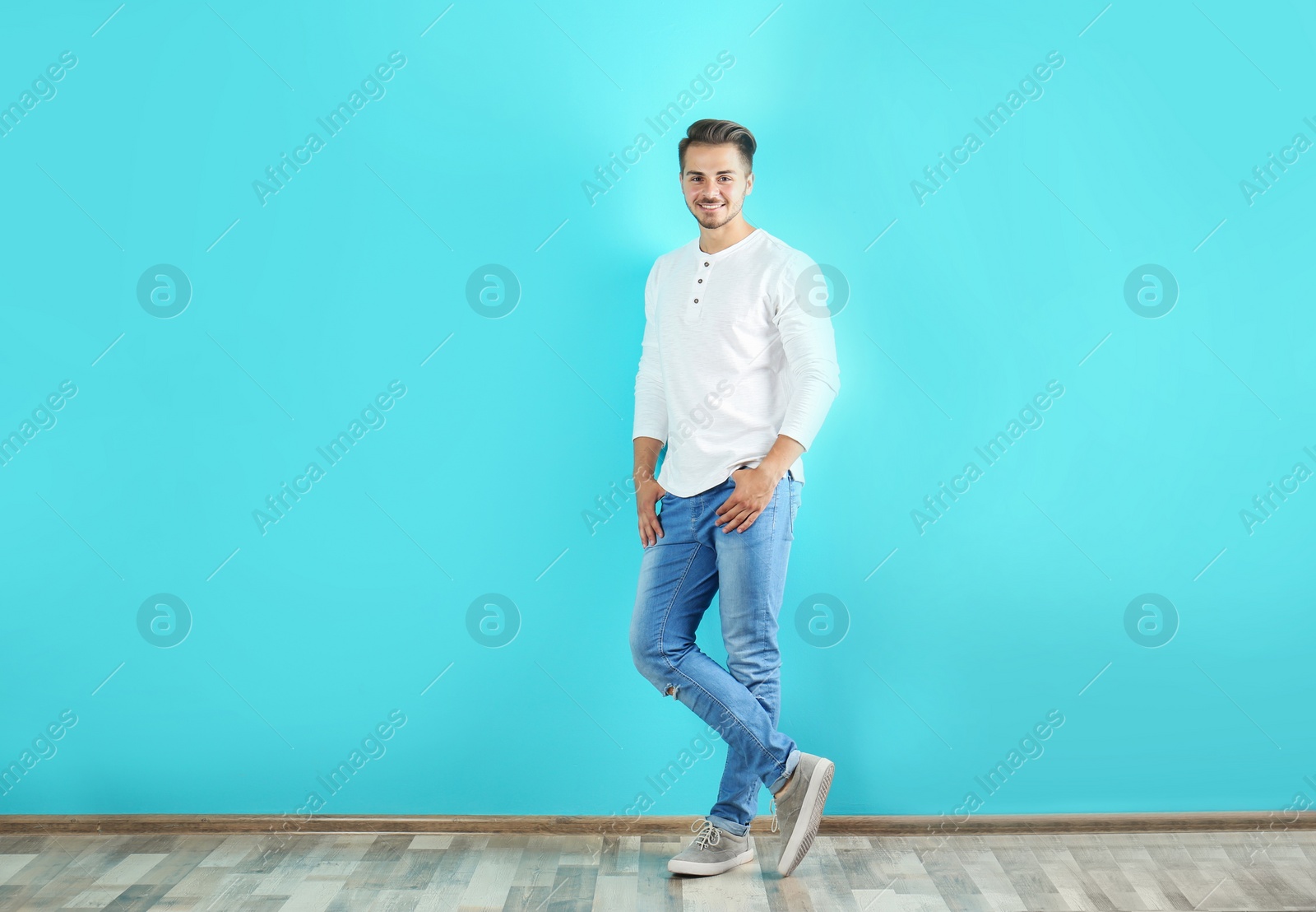 Photo of Young man in stylish jeans near color wall