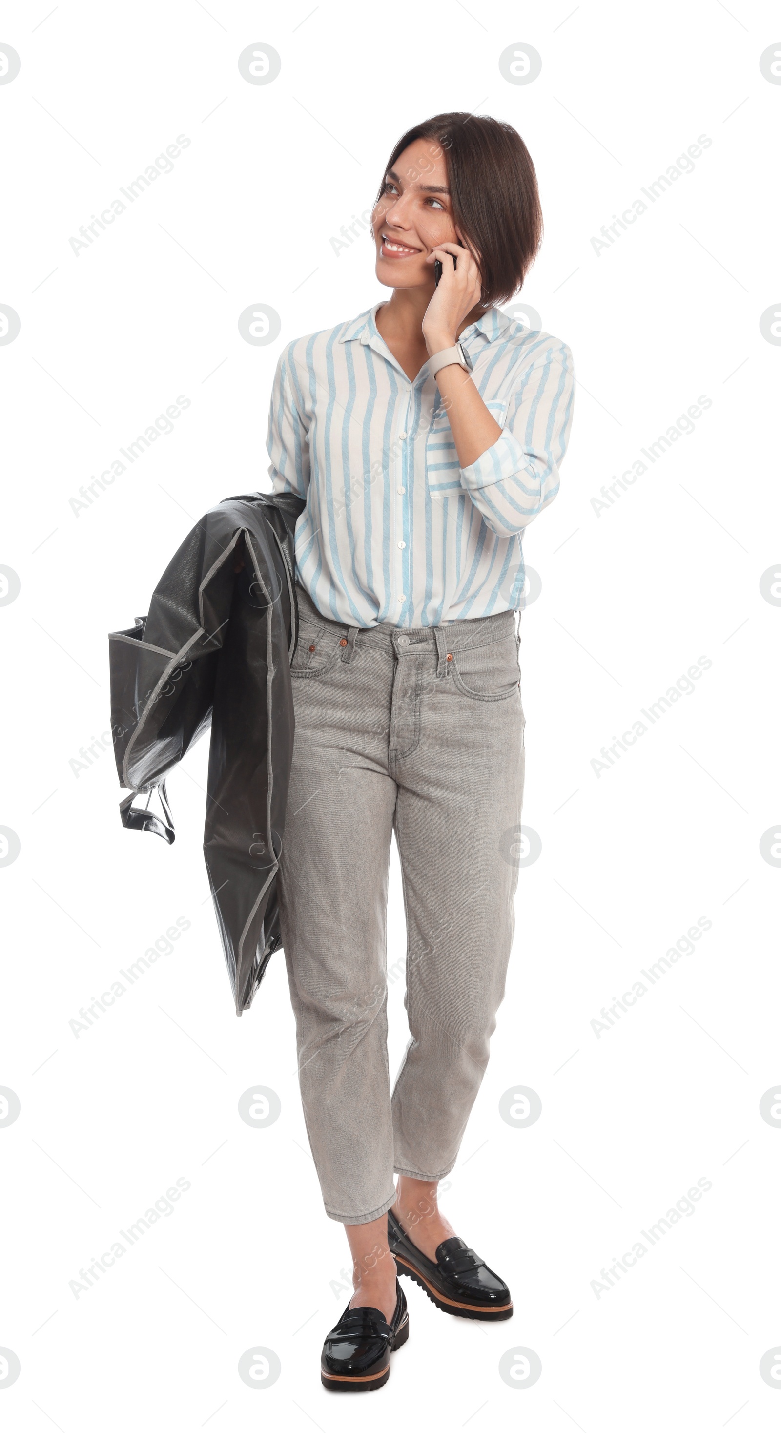 Photo of Woman holding garment cover with clothes while talking on phone, isolated on white. Dry-cleaning service