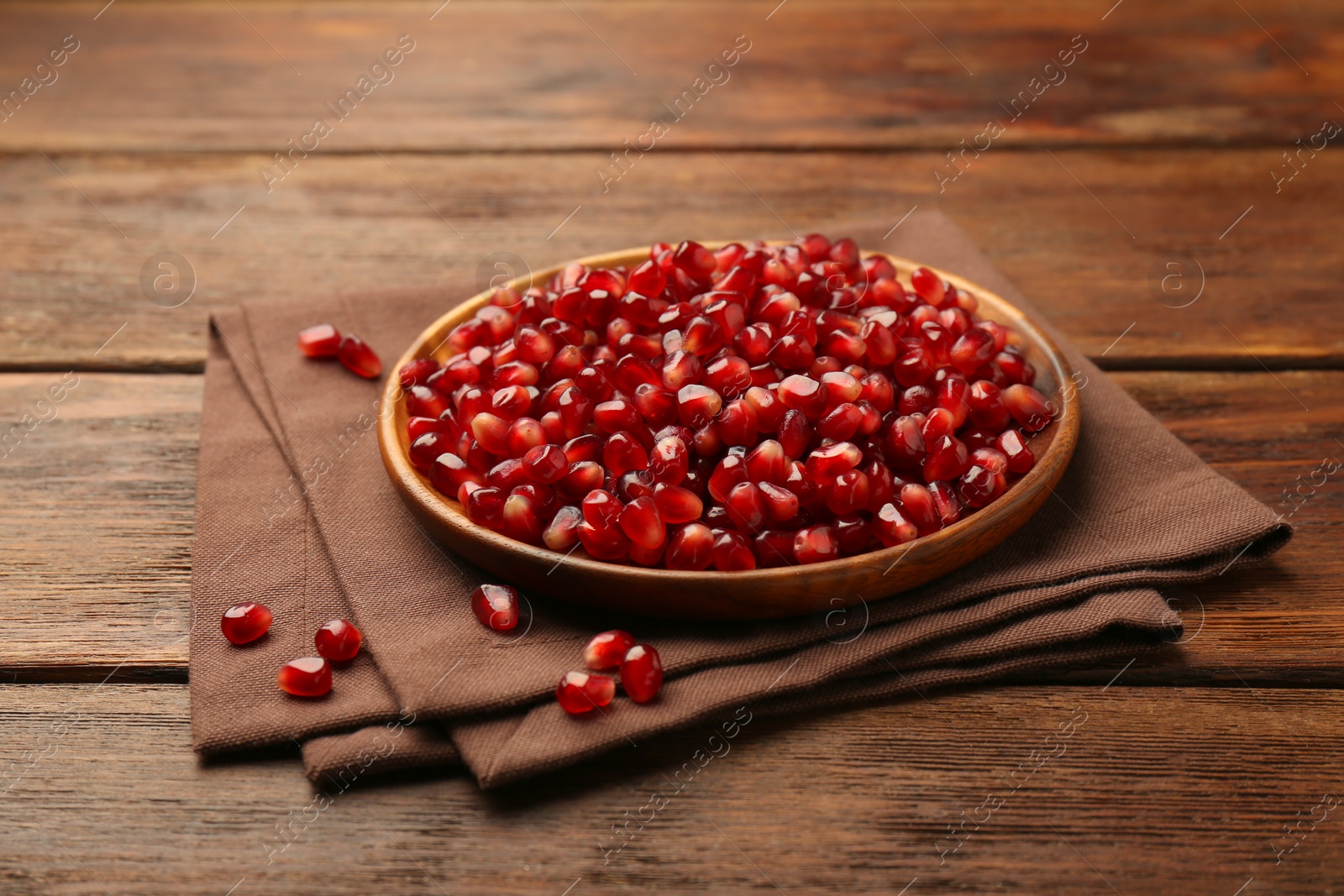 Photo of Tasty ripe pomegranate grains on wooden table