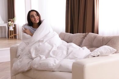 Woman covered in blanket resting on sofa, space for text