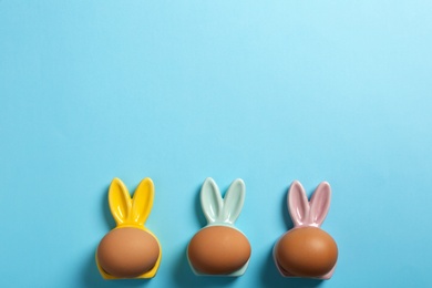 Flat lay composition of Easter bunny ears and eggs on color background, space for text