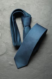 Photo of One blue necktie on grey textured table, top view