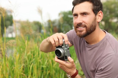 Man with camera outdoors, space for text. Interesting hobby