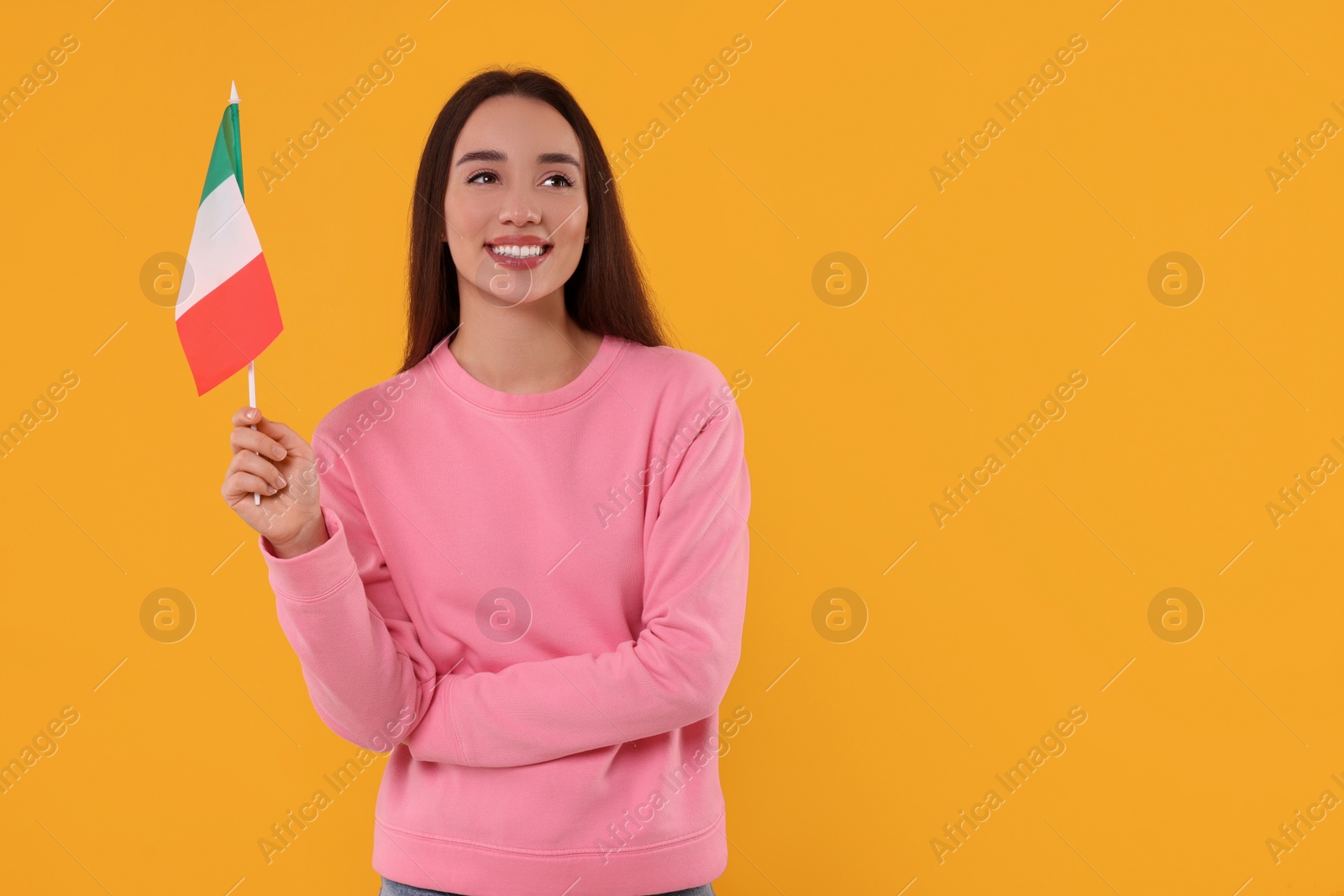 Photo of Young woman holding flag of Italy on orange background, space for text