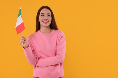 Photo of Young woman holding flag of Italy on orange background, space for text