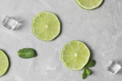 Photo of Flat lay composition with slices of fresh juicy limes on marble table