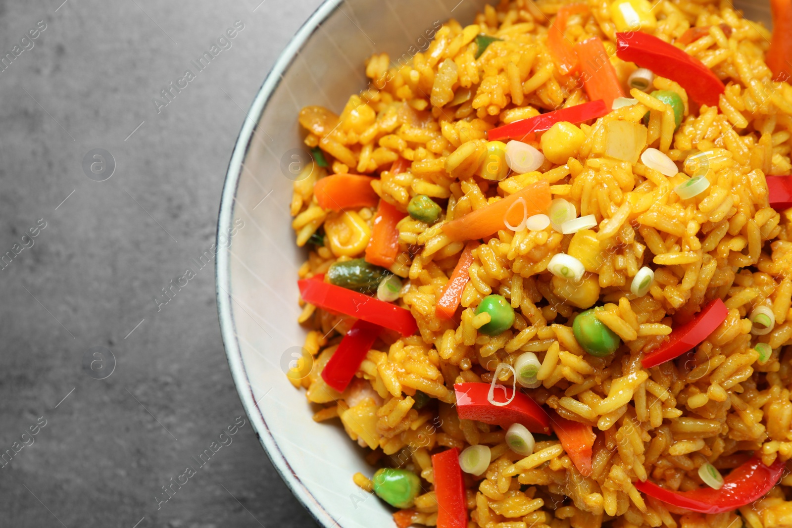 Photo of Delicious rice pilaf with vegetables on grey table