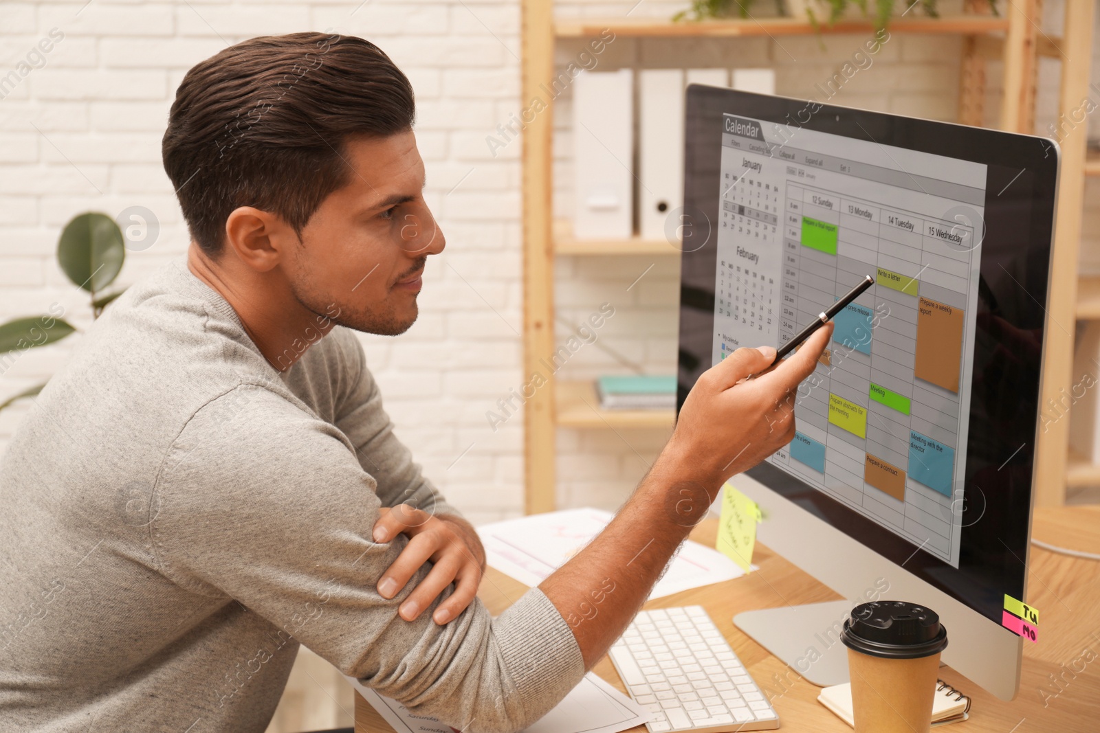 Photo of Handsome man using calendar app on computer in office