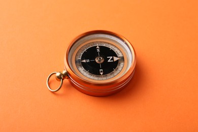 Photo of One compass on orange background. Tourist equipment