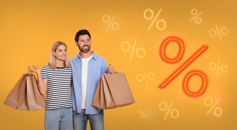 Image of Discount offer. Couple with shopping bags looking at percent signs on orange background, banner design