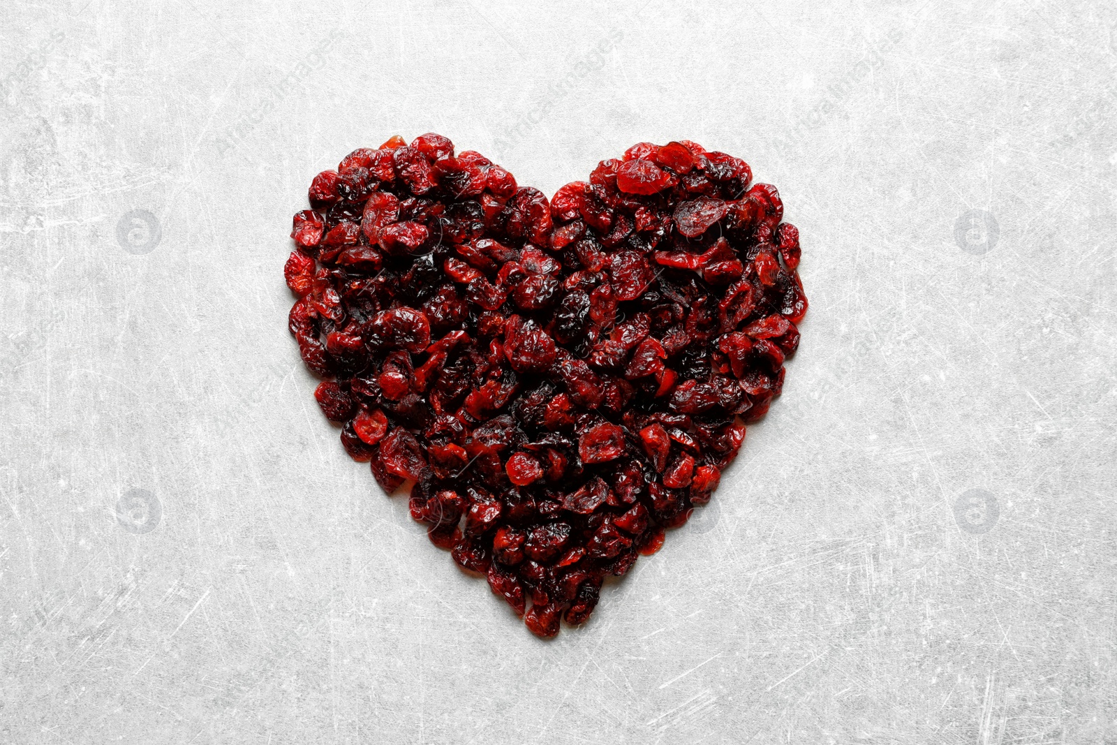 Photo of Heart shaped heap of sweet cranberries on color background, top view. Dried fruit as healthy snack