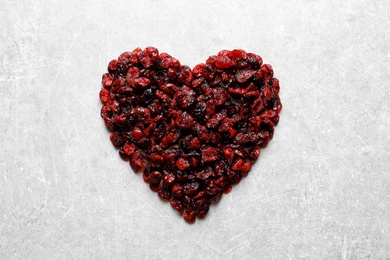 Photo of Heart shaped heap of sweet cranberries on color background, top view. Dried fruit as healthy snack