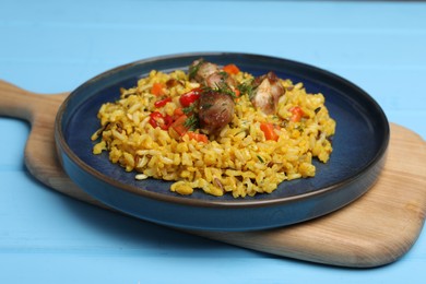 Photo of Delicious pilaf with meat, carrot and chili pepper on light blue wooden table, closeup