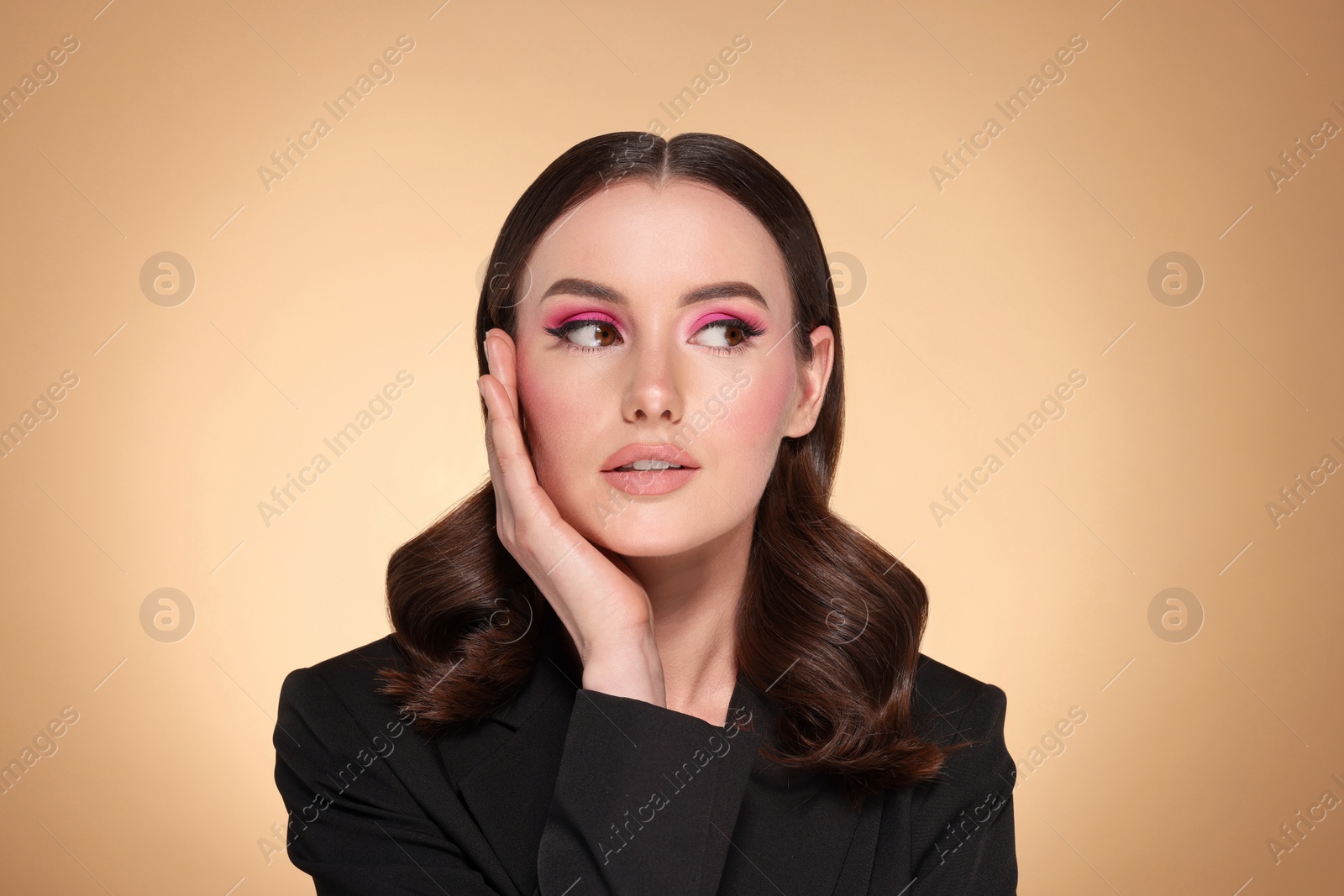 Photo of Portrait of beautiful young woman with makeup and gorgeous hair styling on beige background