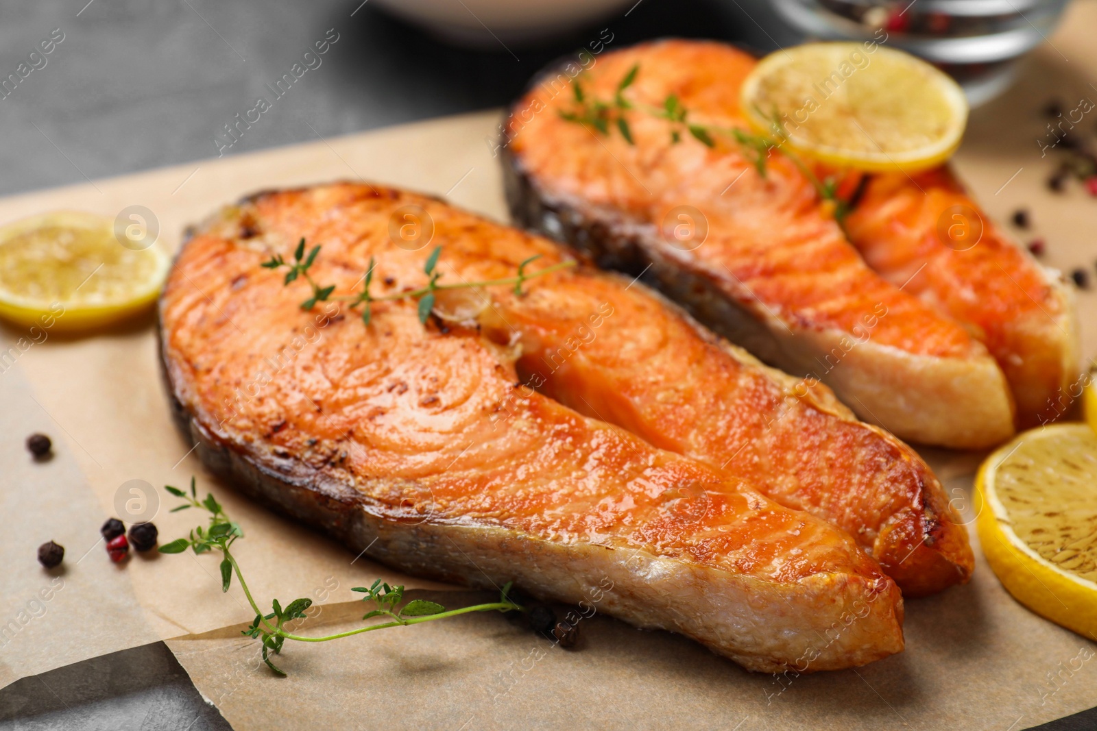 Photo of Delicious roasted fish with thyme and lemon on parchment paper, closeup