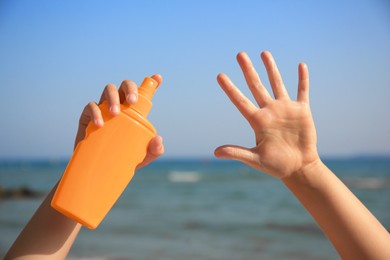 Photo of Child with bottlesunscreen near sea, closeup. Sun protection care