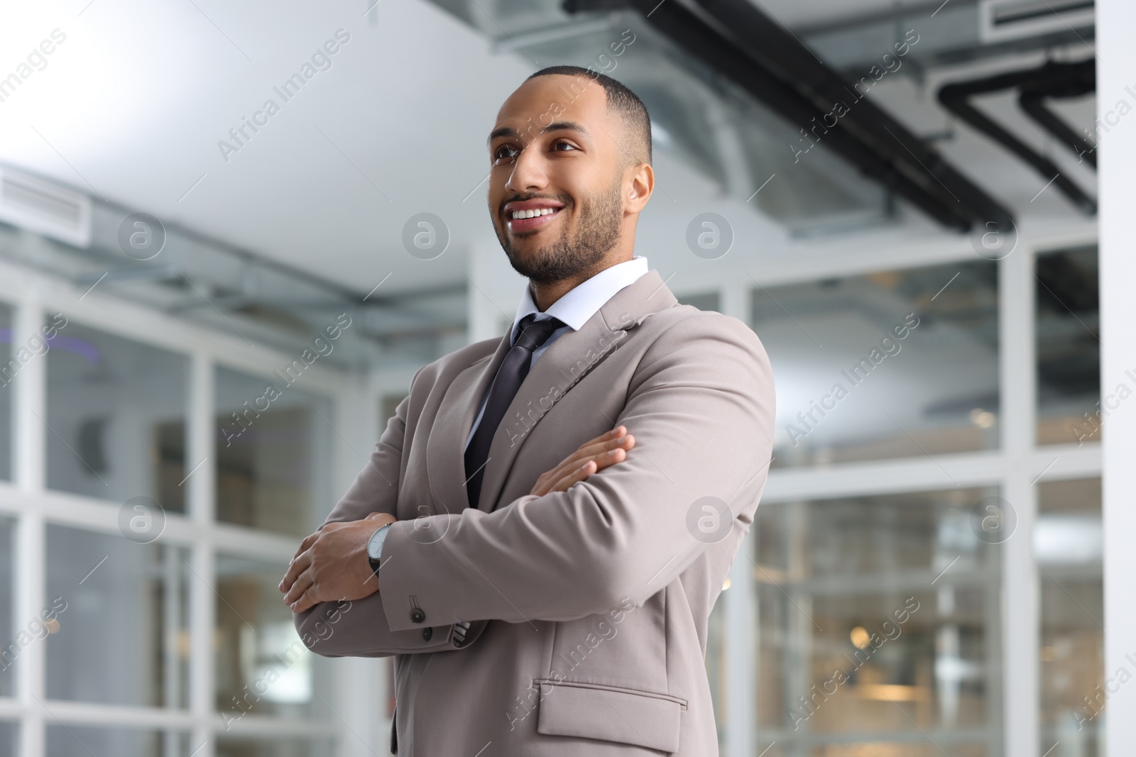 Photo of Happy man with crossed arms in office, low angle view. Lawyer, businessman, accountant or manager