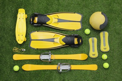 Different sport equipment on green grass, flat lay