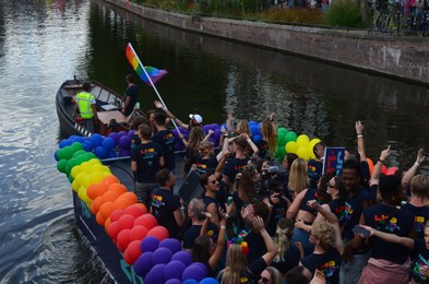 Photo of AMSTERDAM, NETHERLANDS - AUGUST 06, 2022: Many people in boats at LGBT pride parade on river