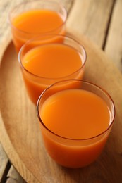 Glasses of freshly made carrot juice on wooden plate