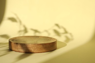 Photo of Presentation of product. Wooden podium on yellow background. Space for text