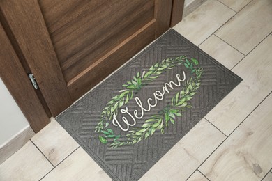 Photo of Beautiful doormat with word Welcome on floor near entrance, above view