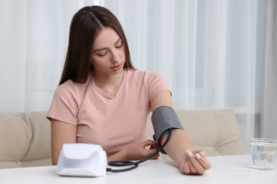 Woman measuring blood pressure with tonometer at home