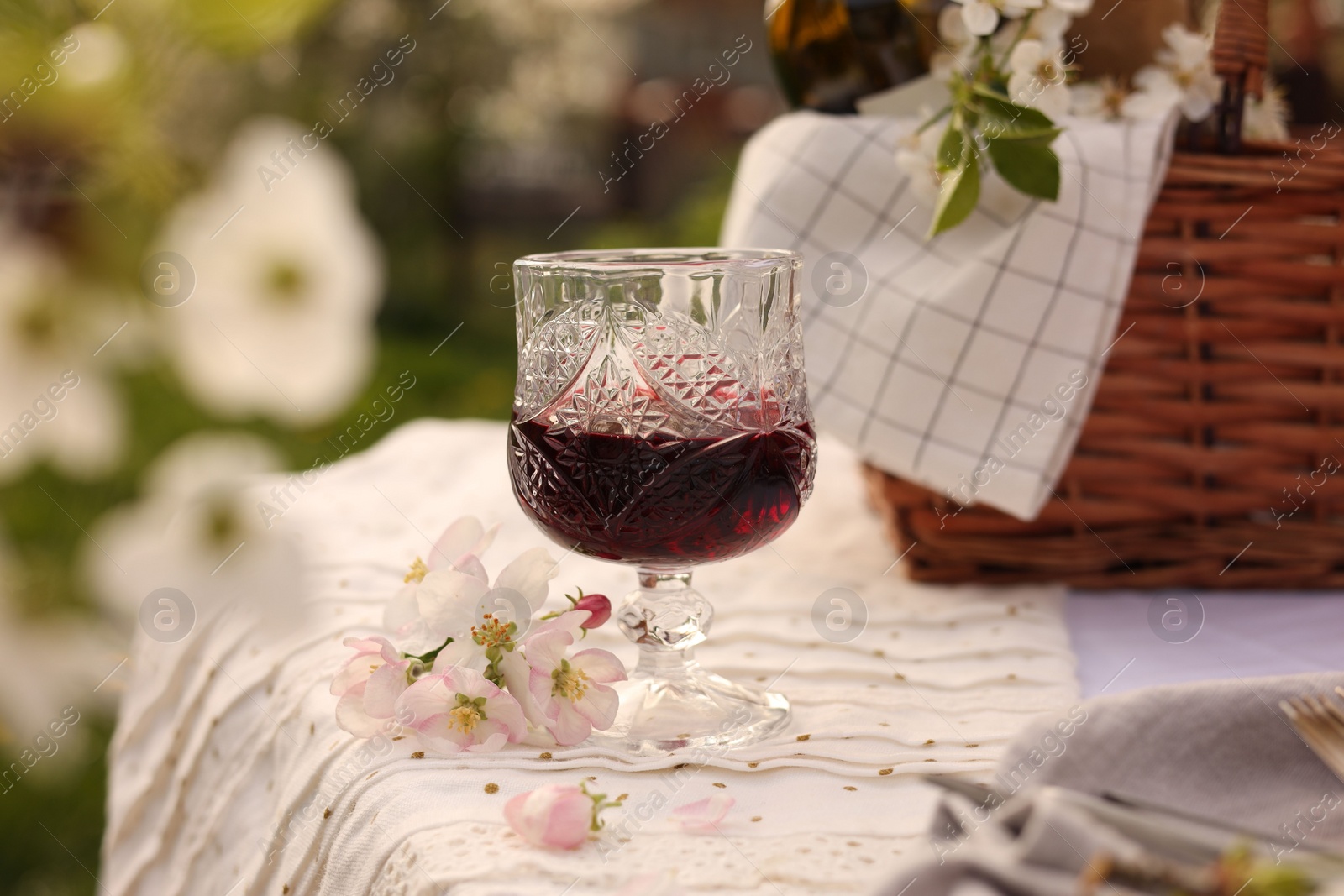 Photo of Stylish table setting with beautiful spring flowers and wine in garden