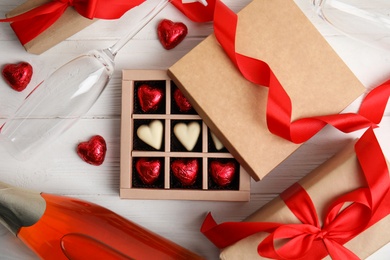 Photo of Flat lay composition with heart shaped chocolate candies on white wooden table. Happy Valentine's day