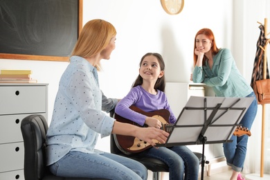 Little girl with her teacher and mother at music lesson. Learning notes